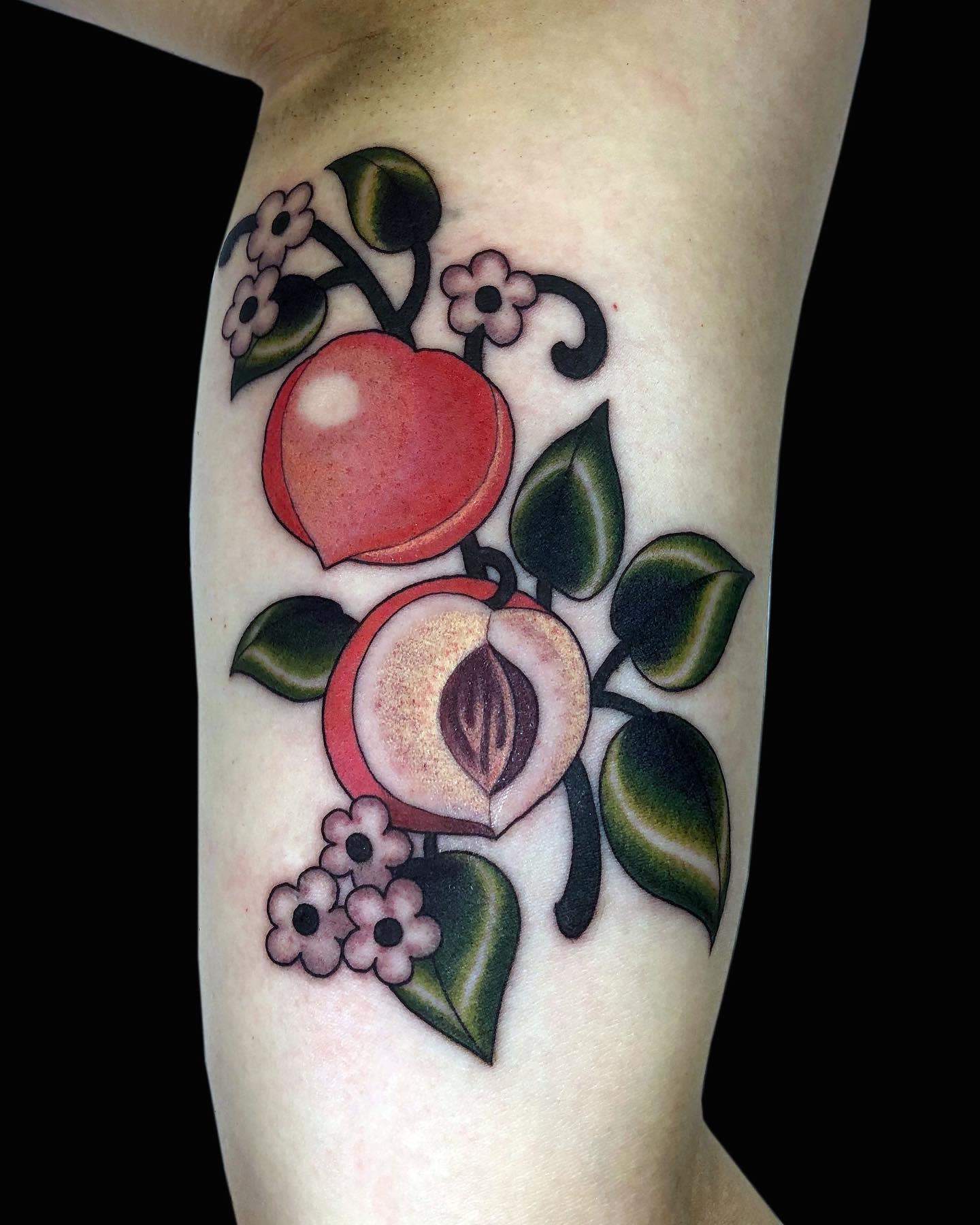 Tattoo of peaches, leaves, and flowers on an arm